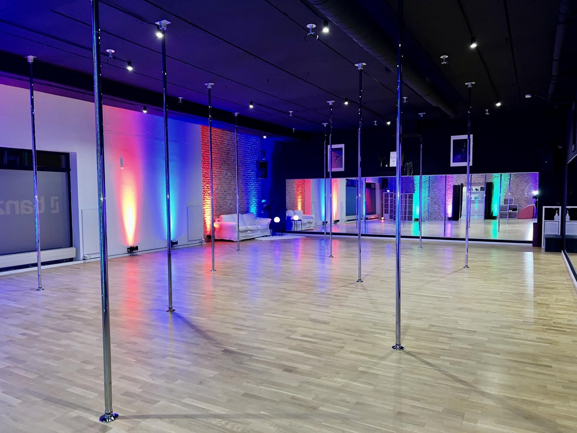 Originalaufnahme des Pole-Arts-Studios in Neunkirchen mit Tanzstangen, Spiegelwand und farbiger Beleuchtung